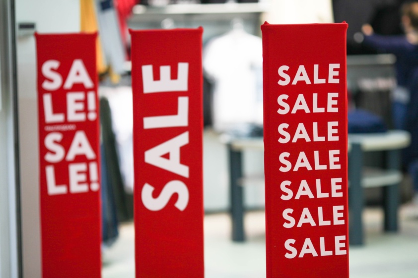 Red bright sale banner on anti-thieft gate sensor at retail shopping mall entrance.